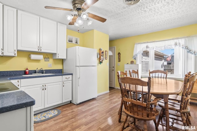 dining area featuring visible vents, light wood-style floors, a ceiling fan, and a textured ceiling