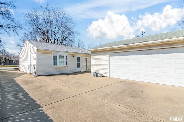 ranch-style home with an outbuilding, a shingled roof, and a garage