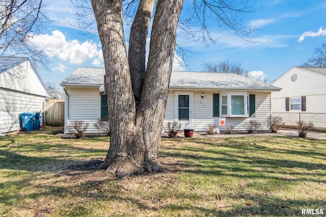 ranch-style home featuring a shingled roof, a front lawn, and fence