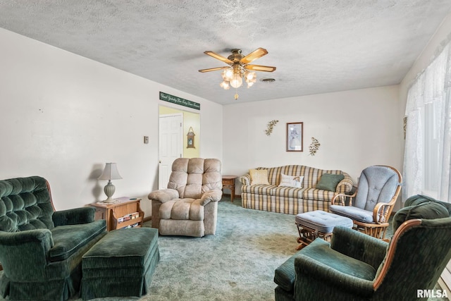 carpeted living room featuring visible vents, a textured ceiling, and a ceiling fan