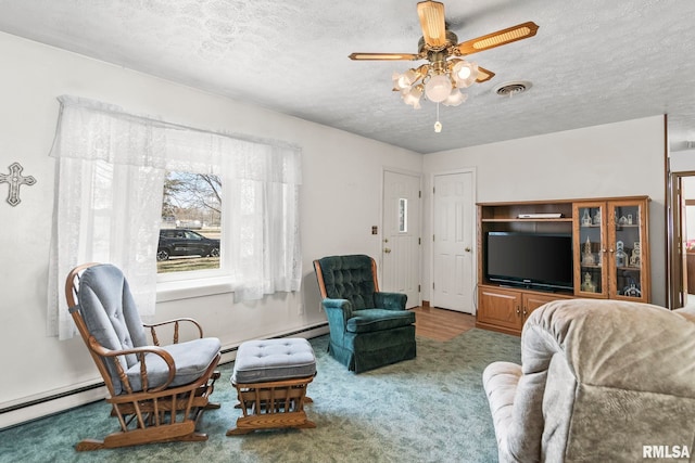 living room with visible vents, a baseboard heating unit, ceiling fan, carpet floors, and a textured ceiling