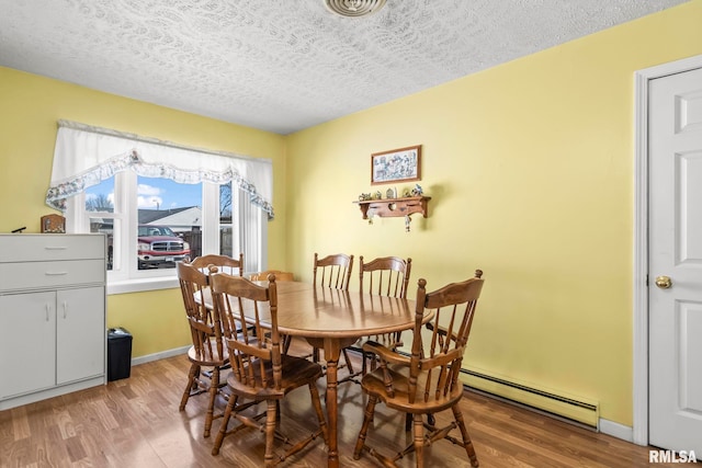 dining room featuring baseboards, a textured ceiling, and wood finished floors