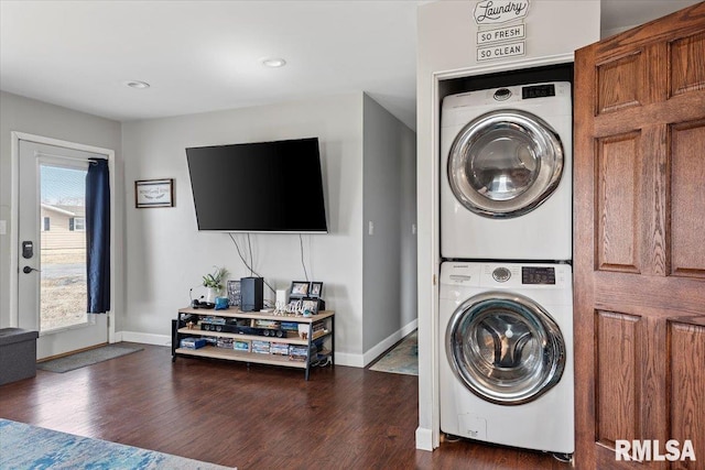 laundry area with laundry area, stacked washer / dryer, wood finished floors, and baseboards