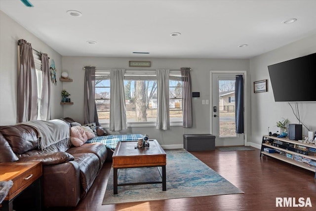 living area with baseboards, a healthy amount of sunlight, and wood finished floors