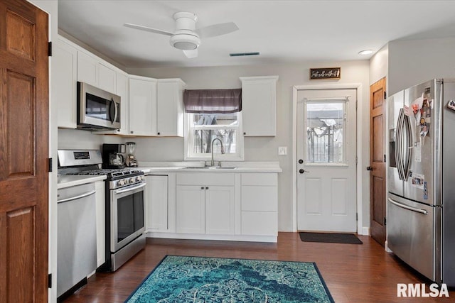 kitchen featuring light countertops, appliances with stainless steel finishes, dark wood-style floors, white cabinetry, and a sink