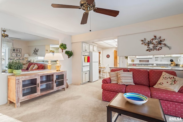 carpeted living room featuring a ceiling fan and a sink