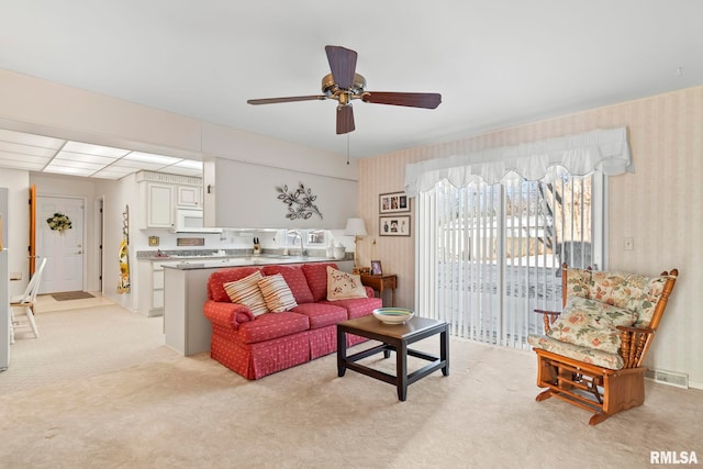 living room featuring light carpet, wallpapered walls, and ceiling fan