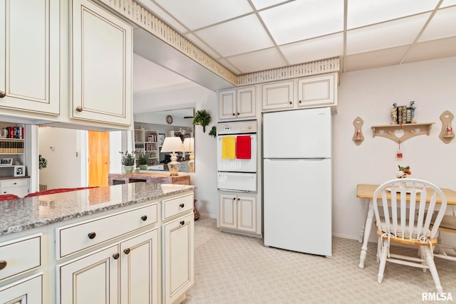 kitchen with white appliances, a warming drawer, a paneled ceiling, and light stone countertops