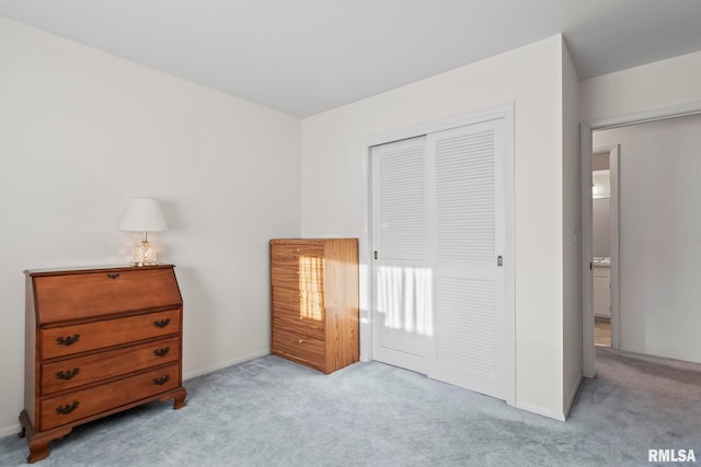 bedroom with a closet, light carpet, and baseboards