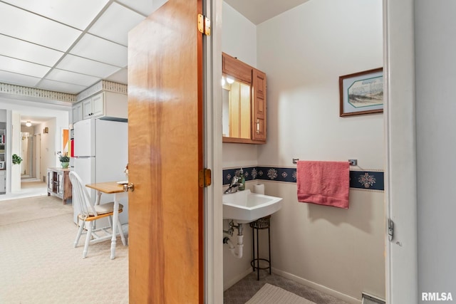 bathroom featuring a paneled ceiling and a sink