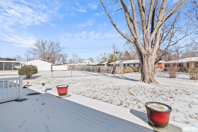 snowy yard featuring a residential view and fence