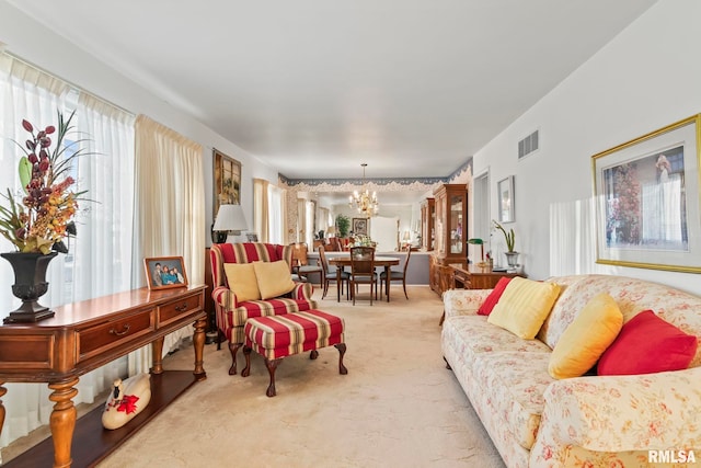 living area with visible vents, light carpet, and an inviting chandelier