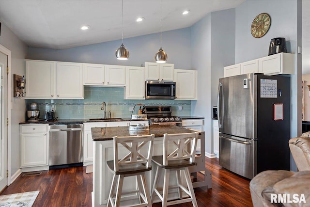 kitchen with a sink, a kitchen island, appliances with stainless steel finishes, white cabinets, and dark wood-style flooring