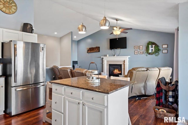 kitchen featuring open floor plan, freestanding refrigerator, a lit fireplace, lofted ceiling, and dark wood-style flooring