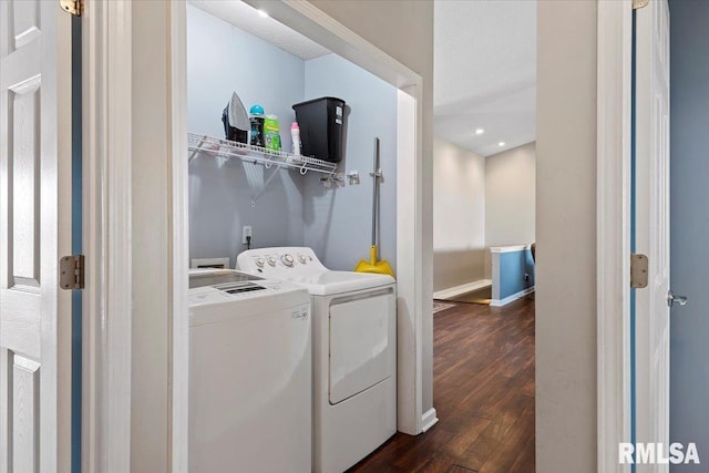 clothes washing area with baseboards, dark wood-style floors, laundry area, and washing machine and clothes dryer