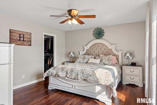 bedroom featuring a closet, a walk in closet, baseboards, and dark wood-style flooring