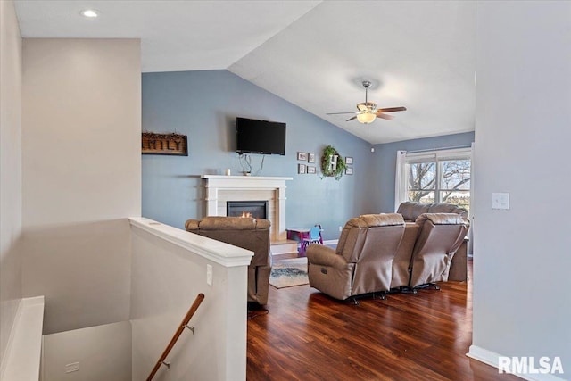 living room with baseboards, lofted ceiling, a glass covered fireplace, a ceiling fan, and dark wood-style flooring