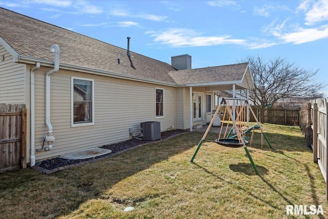 back of property featuring a fenced backyard, a lawn, roof with shingles, and a chimney