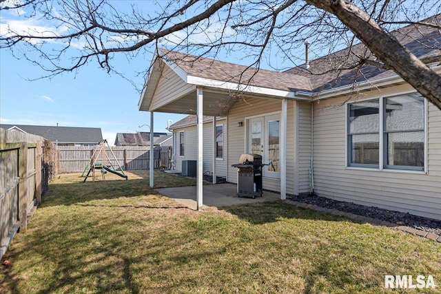 exterior space featuring central air condition unit, a patio, a fenced backyard, a playground, and french doors