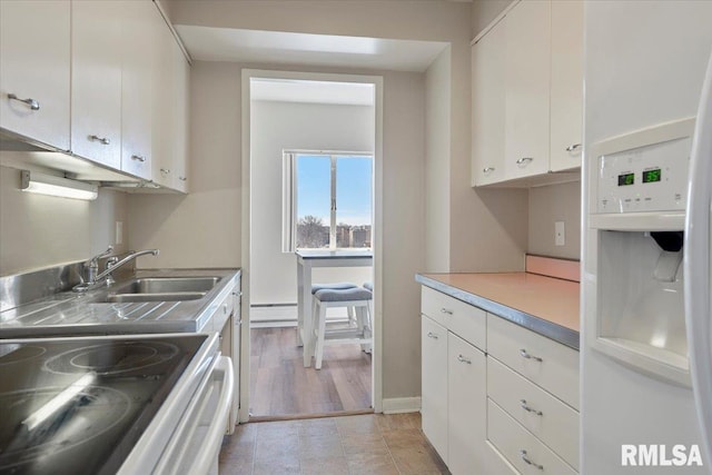 kitchen featuring fridge, range with electric stovetop, baseboard heating, and white cabinetry