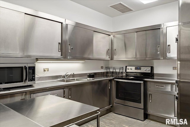 kitchen featuring visible vents, a sink, stainless steel appliances, and stainless steel counters