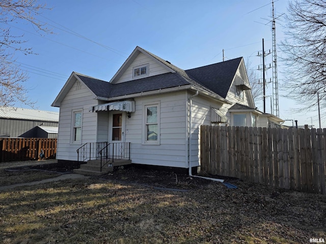 view of front of house with a shingled roof and fence