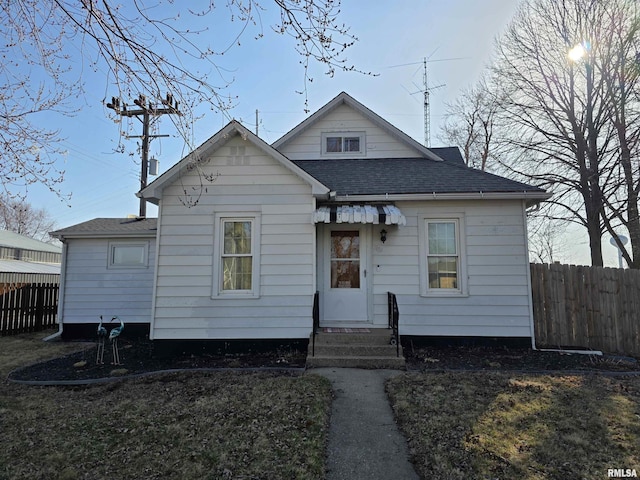 view of front of house with a shingled roof and fence