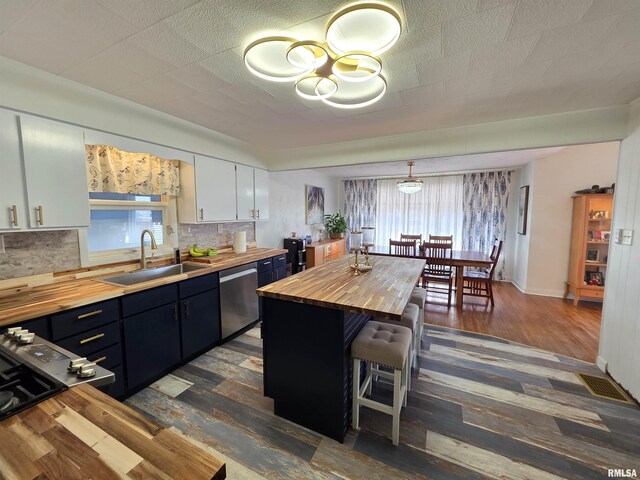 kitchen with a sink, white cabinets, decorative backsplash, wooden counters, and dishwasher