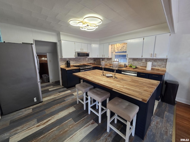 kitchen with tasteful backsplash, dark wood-style flooring, appliances with stainless steel finishes, and butcher block countertops