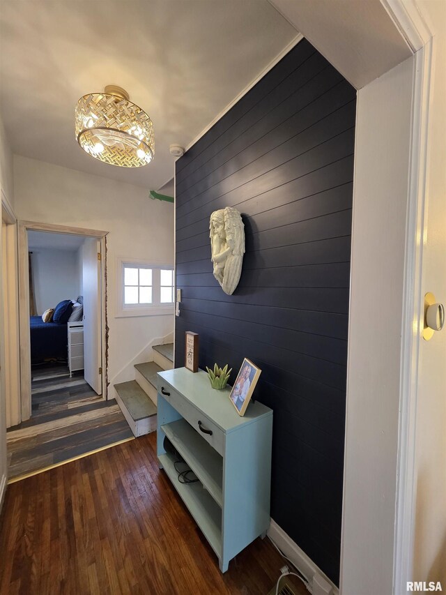 hall with dark wood finished floors, stairway, baseboards, and wooden walls