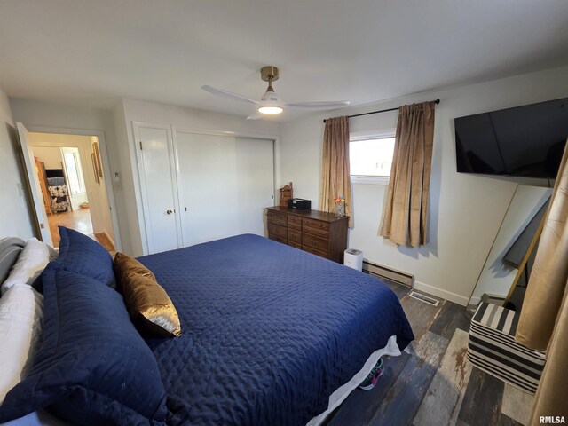 bedroom featuring visible vents, wood finished floors, a closet, a baseboard radiator, and ceiling fan