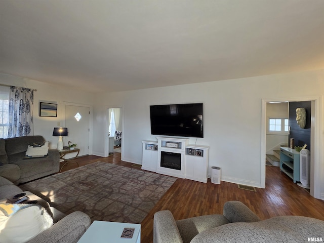 living room featuring visible vents, wood finished floors, stairway, a fireplace, and baseboards