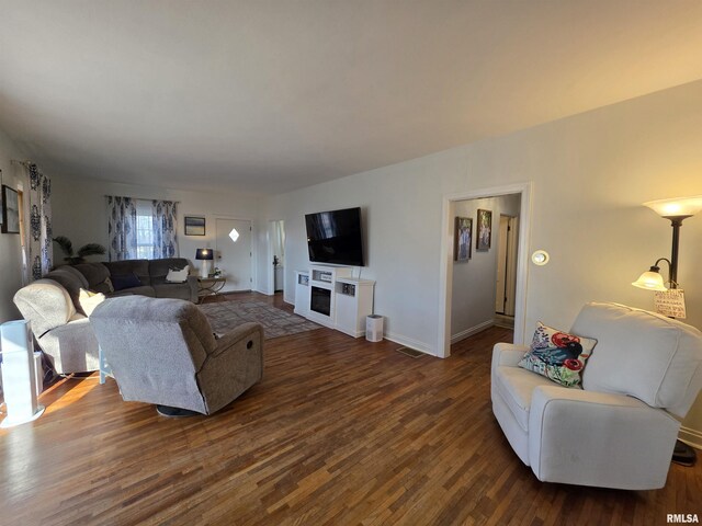 living room with visible vents, baseboards, and dark wood-style flooring