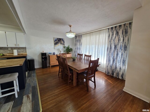 dining space featuring dark wood finished floors, an inviting chandelier, baseboards, and a textured ceiling