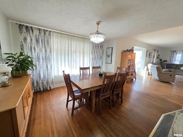 dining space featuring a textured ceiling, dark wood-type flooring, and an inviting chandelier