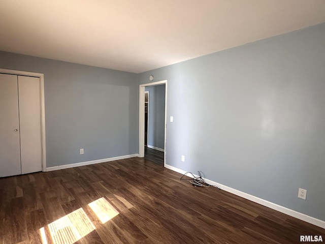 unfurnished bedroom featuring a closet, dark wood-type flooring, and baseboards