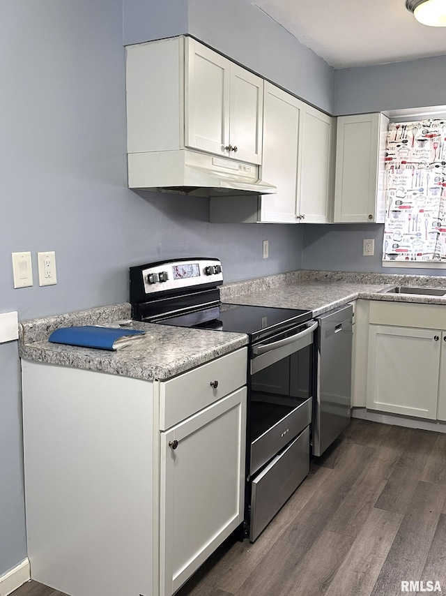 kitchen with under cabinet range hood, white cabinetry, stainless steel appliances, and dark wood-type flooring