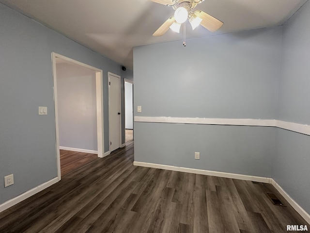 empty room with visible vents, ceiling fan, dark wood-type flooring, and baseboards