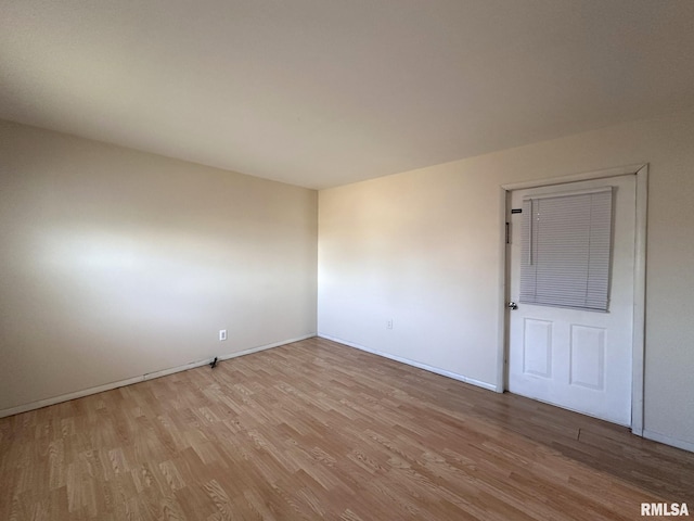 spare room with baseboards and light wood finished floors