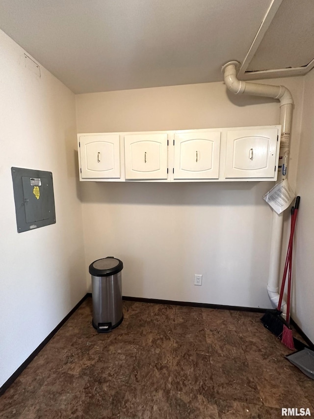 clothes washing area featuring electric panel and baseboards