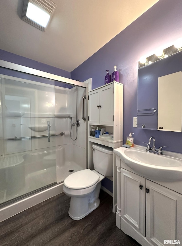 full bathroom featuring a stall shower, toilet, wood finished floors, and vanity