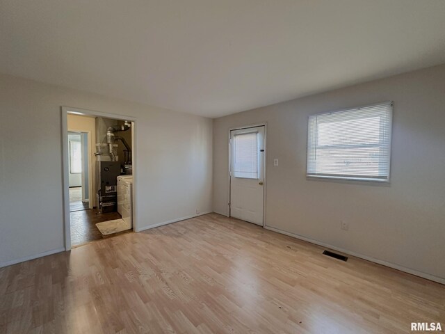 empty room featuring light wood-style floors, visible vents, and baseboards