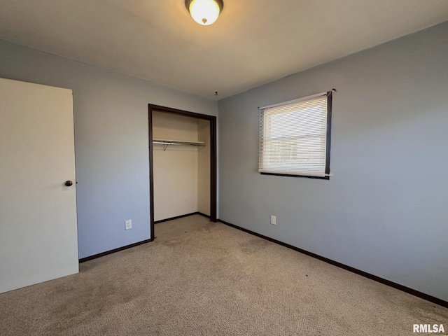 unfurnished bedroom featuring a closet, baseboards, and light colored carpet