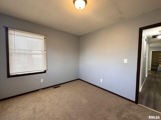 empty room with baseboards, visible vents, and carpet floors