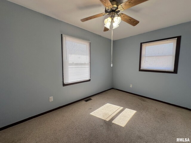 carpeted empty room featuring visible vents, baseboards, and ceiling fan