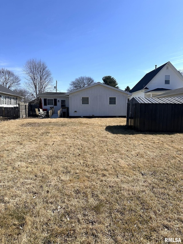 back of house with a yard, an outbuilding, and fence