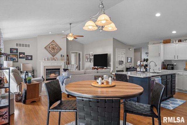 dining area with visible vents, lofted ceiling, a ceiling fan, and light wood finished floors