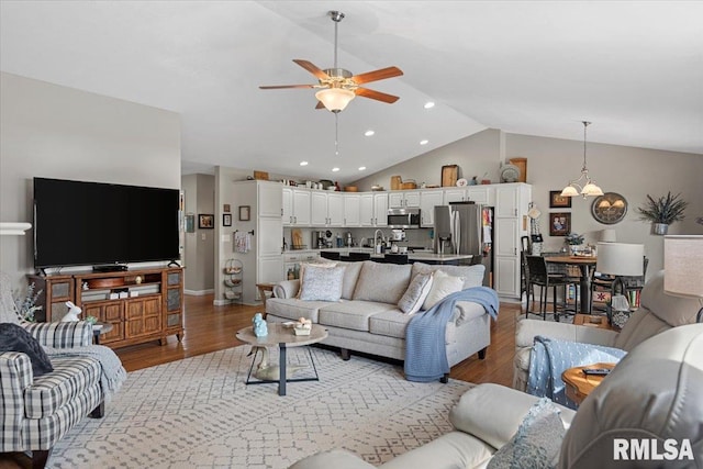 living room with recessed lighting, ceiling fan with notable chandelier, wood finished floors, and vaulted ceiling