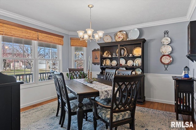 dining area featuring a chandelier, crown molding, baseboards, and wood finished floors