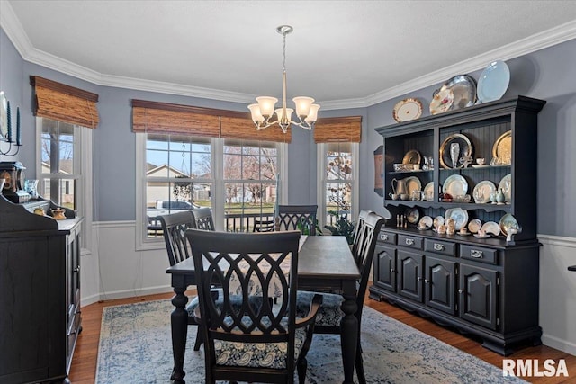 dining room with a chandelier, plenty of natural light, dark wood finished floors, and wainscoting